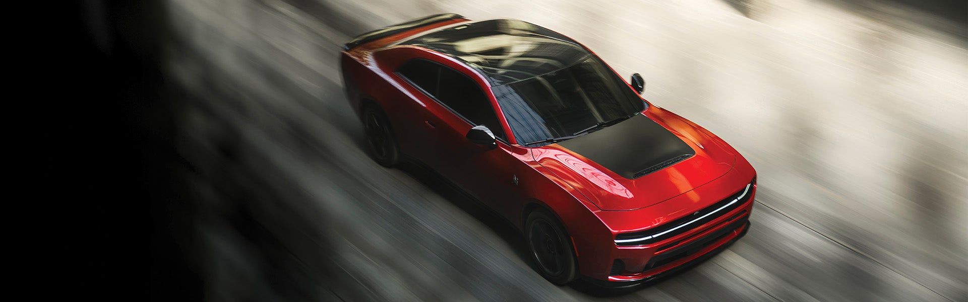 Red 2026 Dodge Charger driving on a blurred roadway from an overhead front angle.