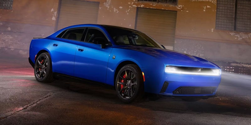 Blue 2026 Dodge Charger parked at night with its front LED light bar illuminated.