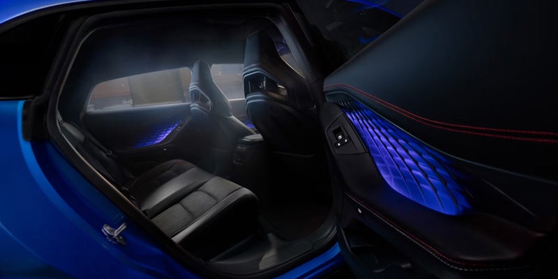 Interior of a 2026 Dodge Charger showing black seats, a digital dashboard, and blue ambient door lighting.
