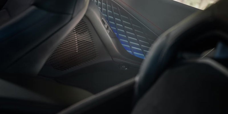 Close-up of the 2026 Dodge Charger interior door panel with blue ambient lighting and patterned trim.