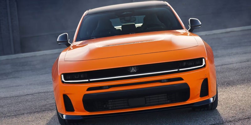 Orange 2026 Dodge Charger shown from the front with slim LED headlights and a wide lower grille.