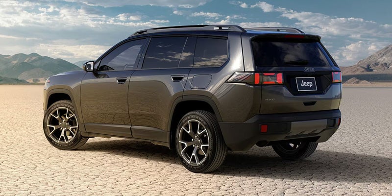 Gray 2026 Jeep Cherokee shown from the rear three-quarter angle on a dry desert landscape.