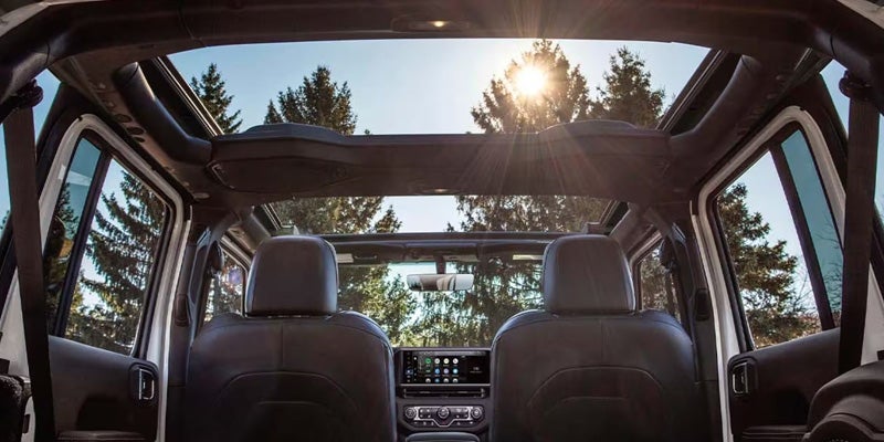 2026 Jeep Wrangler interior with open roof and sunlight.